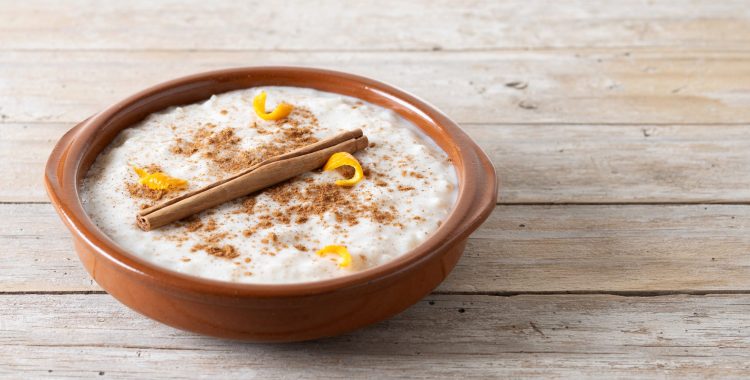 Arroz con leche. Rice pudding with cinnamon in clay bowl on wooden table